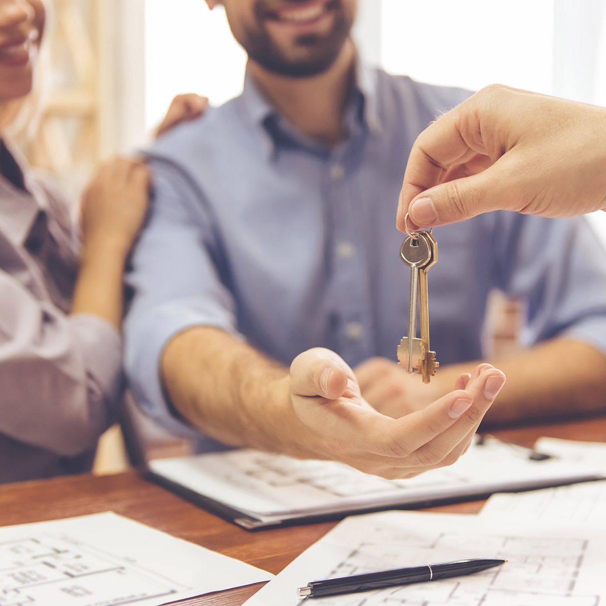 Cropped image of beautiful couple taking keys from the realtor and smiling